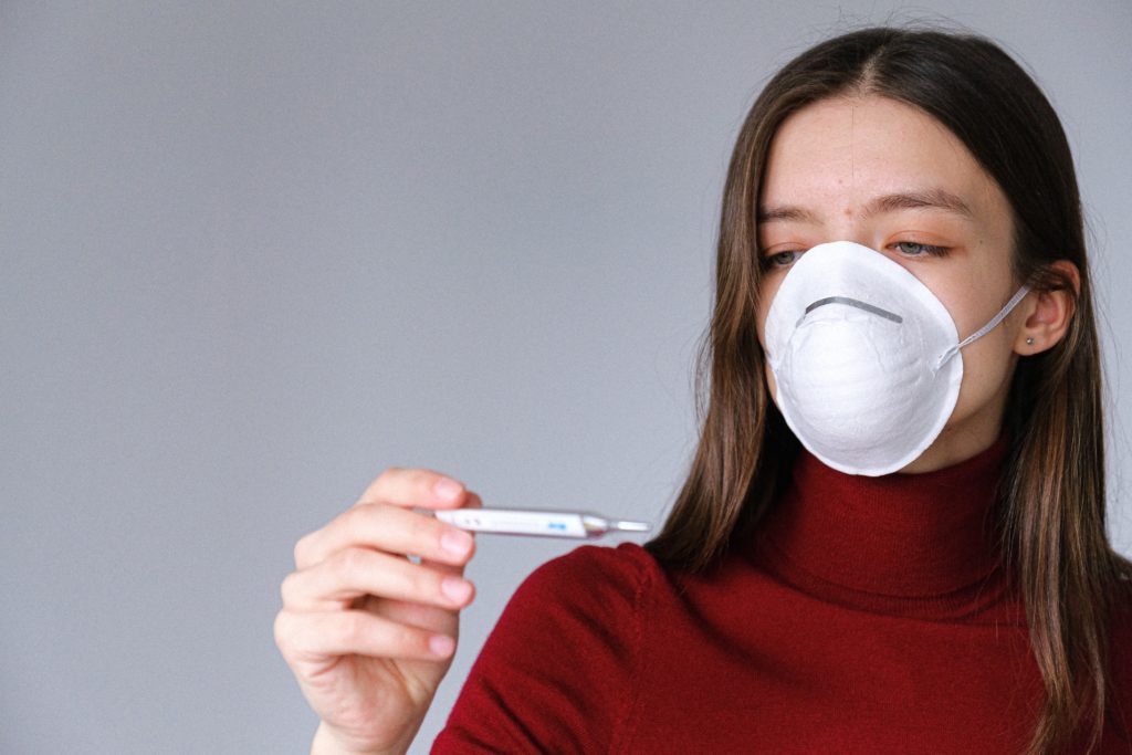 a woman wearing a mask and holding a thermometer