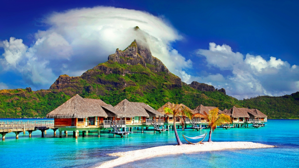 a group of huts on water with Bora Bora in the background