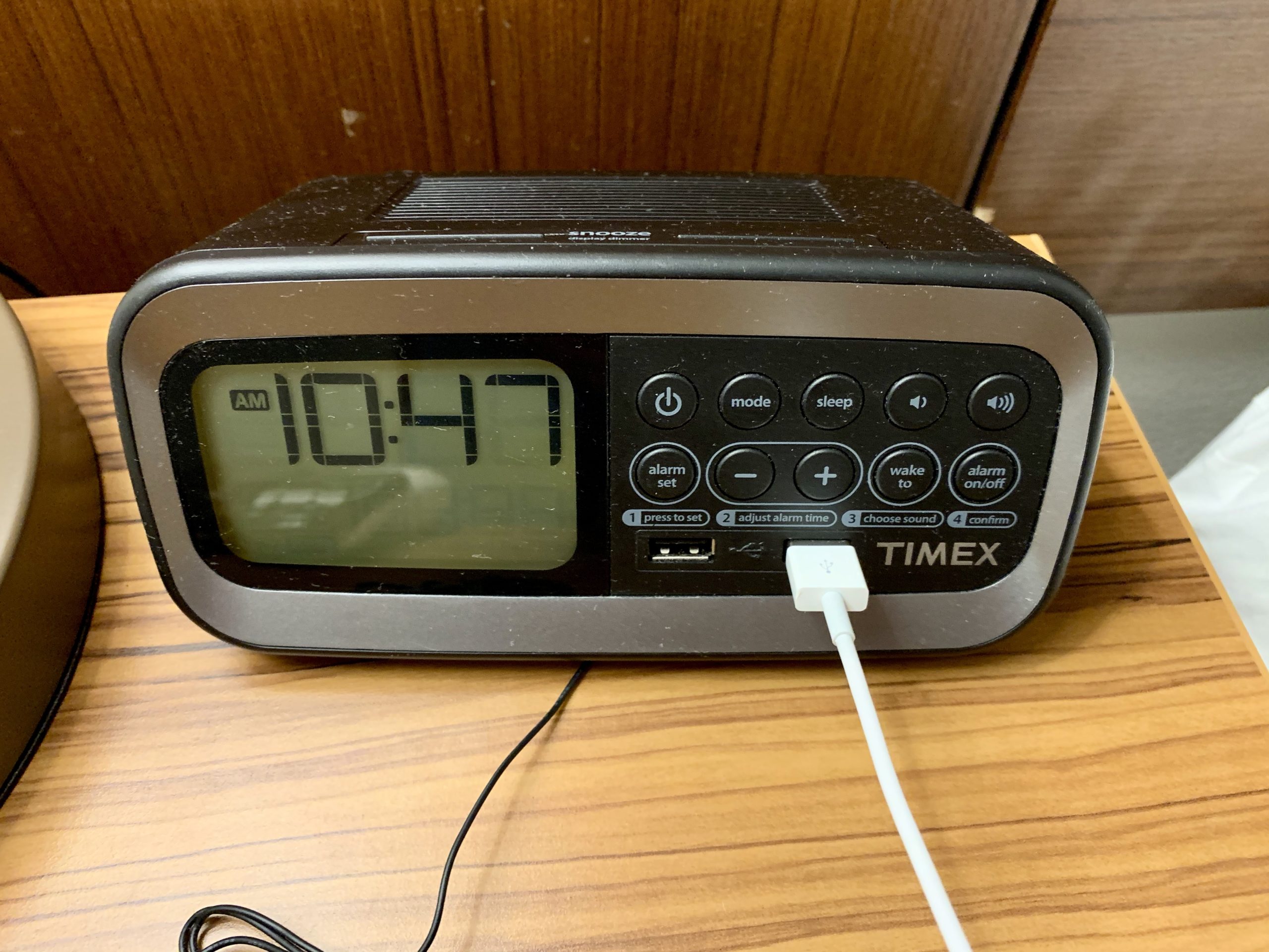 a black and silver digital clock with a white cord plugged into it