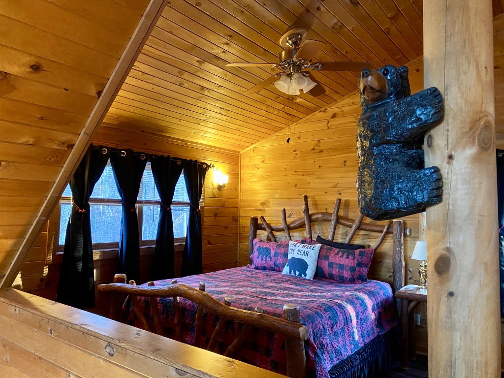 a wooden bedroom with a bed and a bear statue
