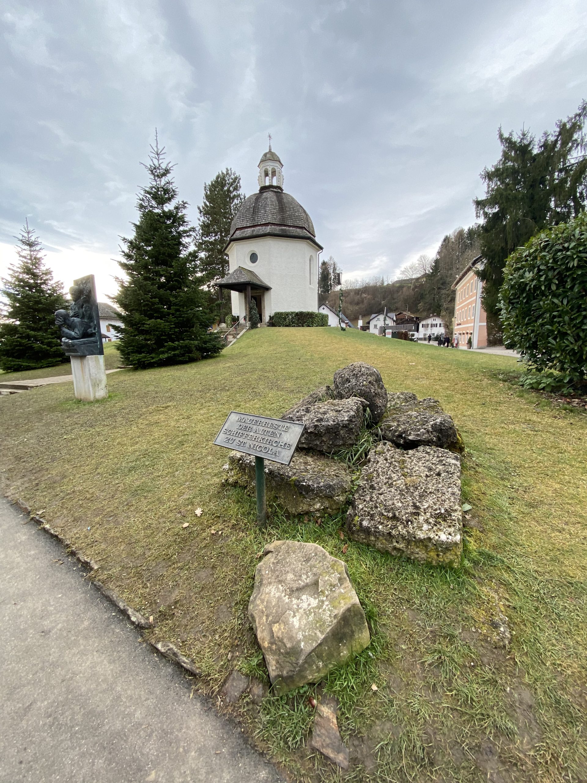 a small white building with a dome and rocks in front of it