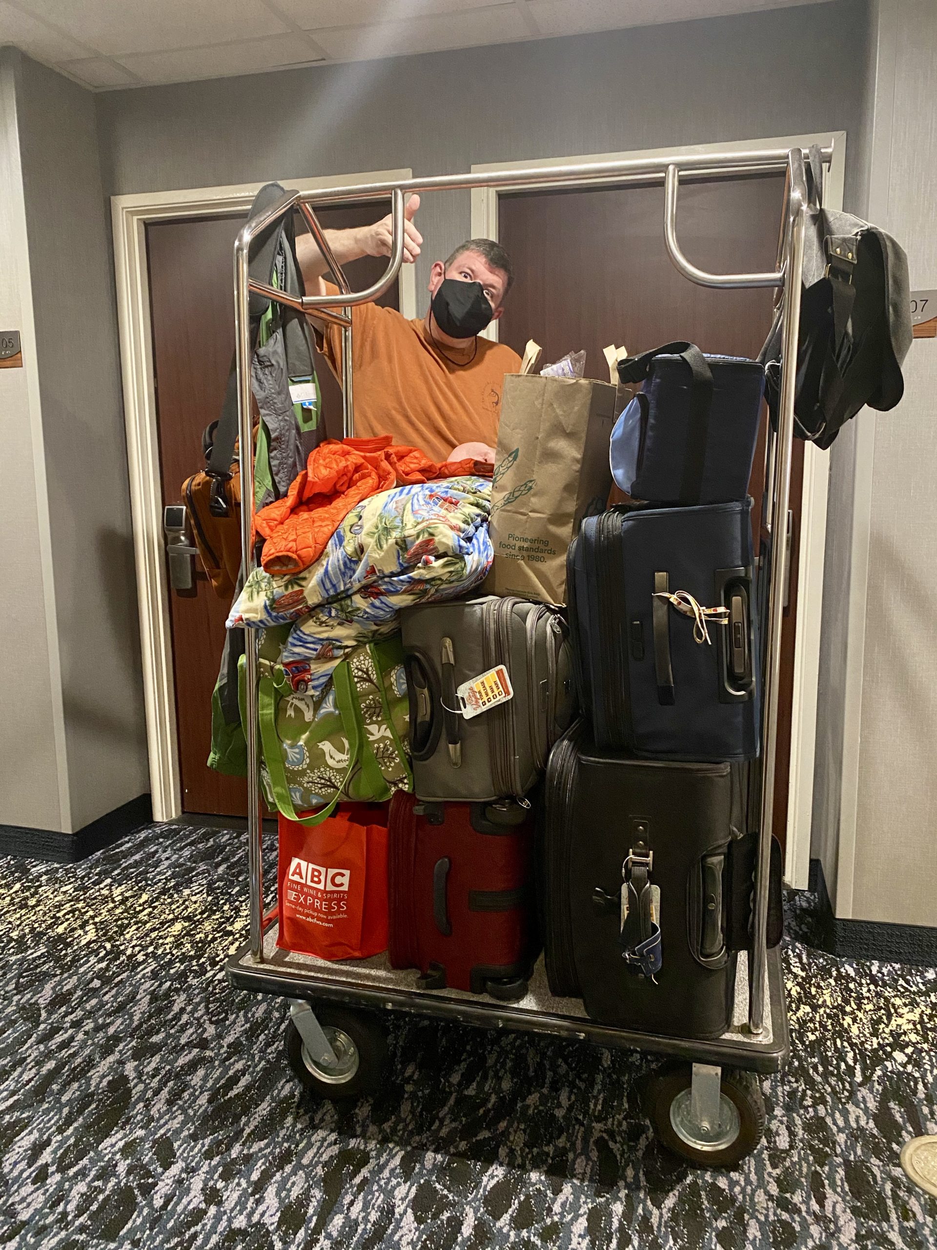 a man wearing a mask standing in a room with luggage