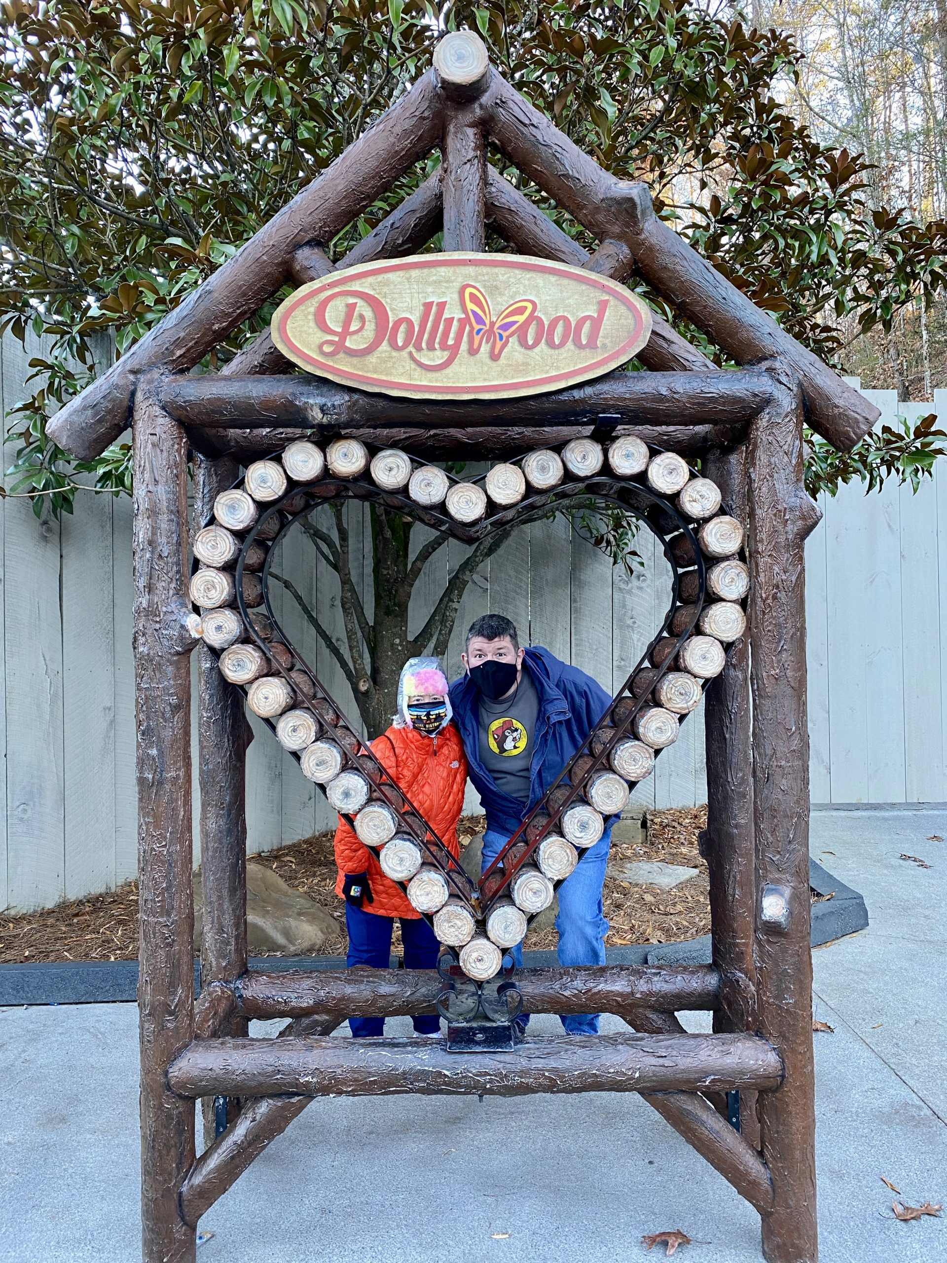 a couple of people posing for a picture in a heart shaped wooden structure