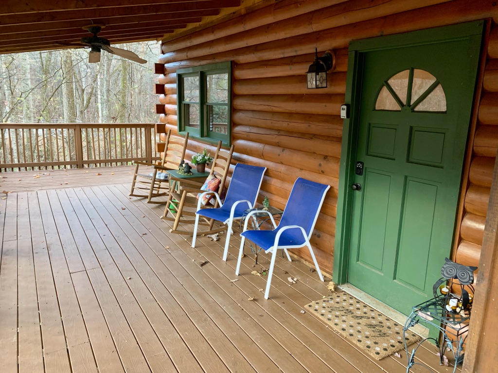 a porch with chairs and a green door