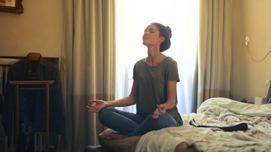 a woman sitting on a bed with her eyes closed