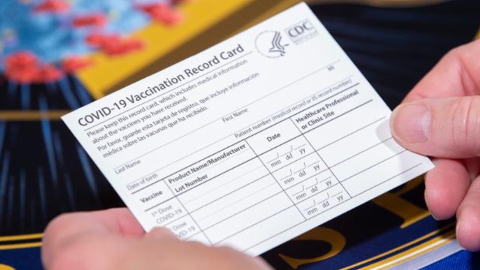 a hand holding a vaccination record card
