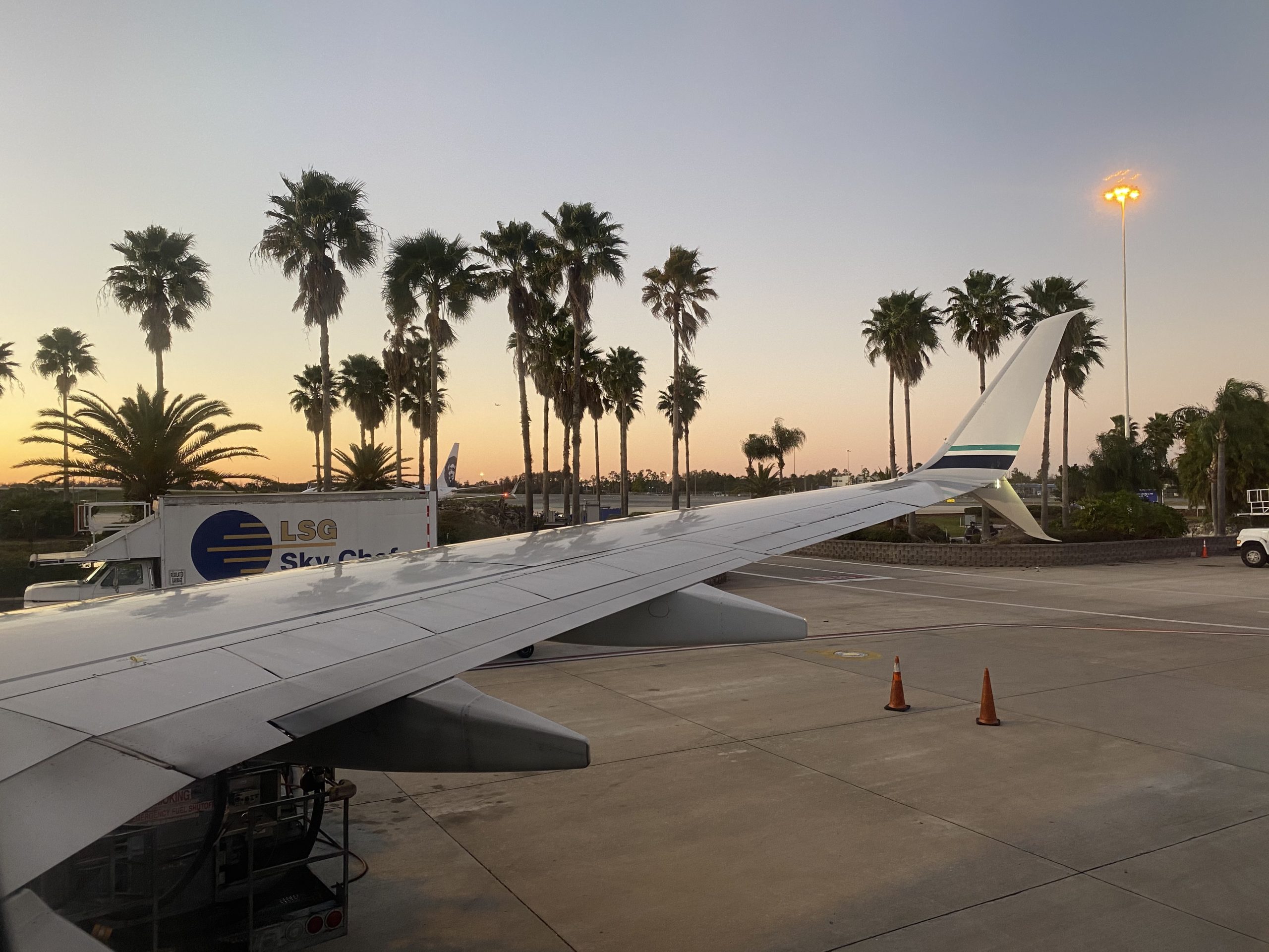 an airplane wing on a runway with palm trees