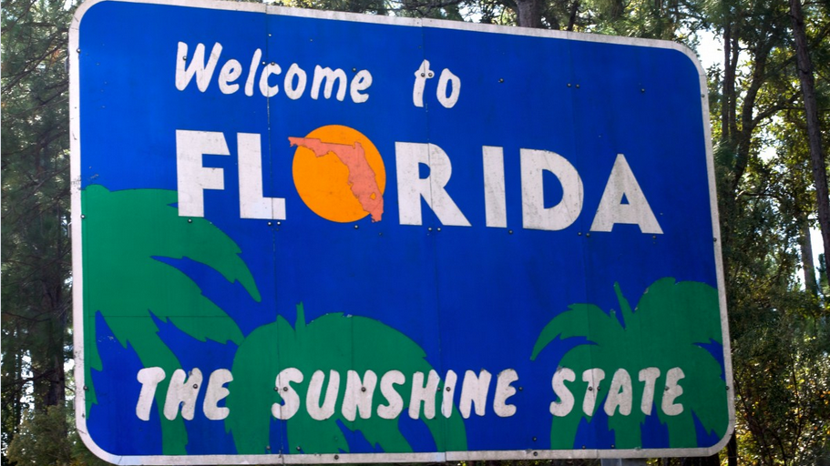 a blue sign with white text and orange sun and palm trees