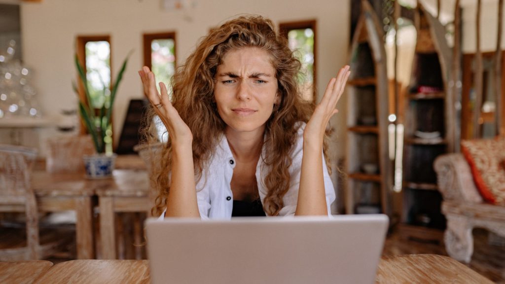 a woman with her hands in her mouth looking at a laptop