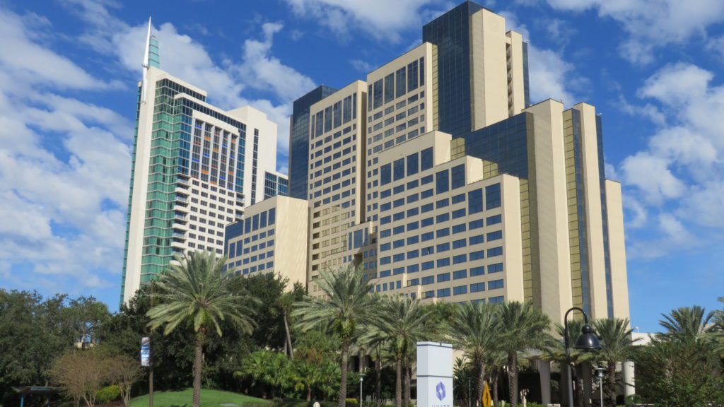 a tall building with palm trees with Hyatt Regency Orlando in the background