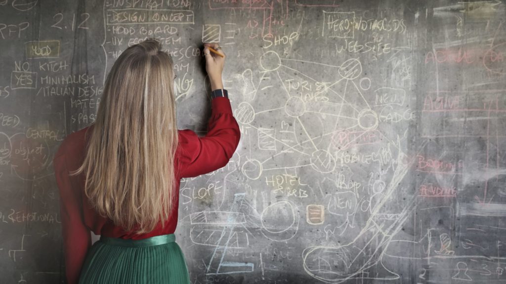 a woman writing on a chalkboard