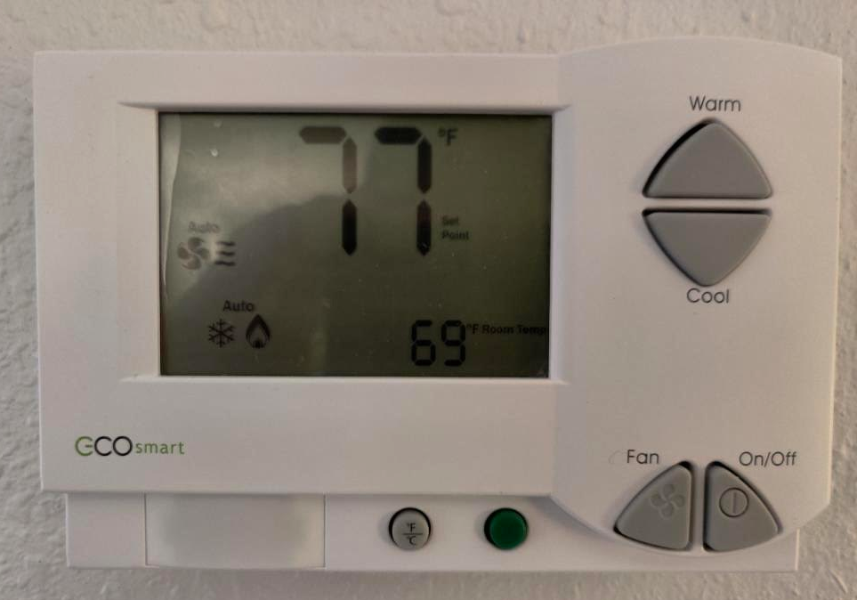 a white digital thermostat with buttons and a display