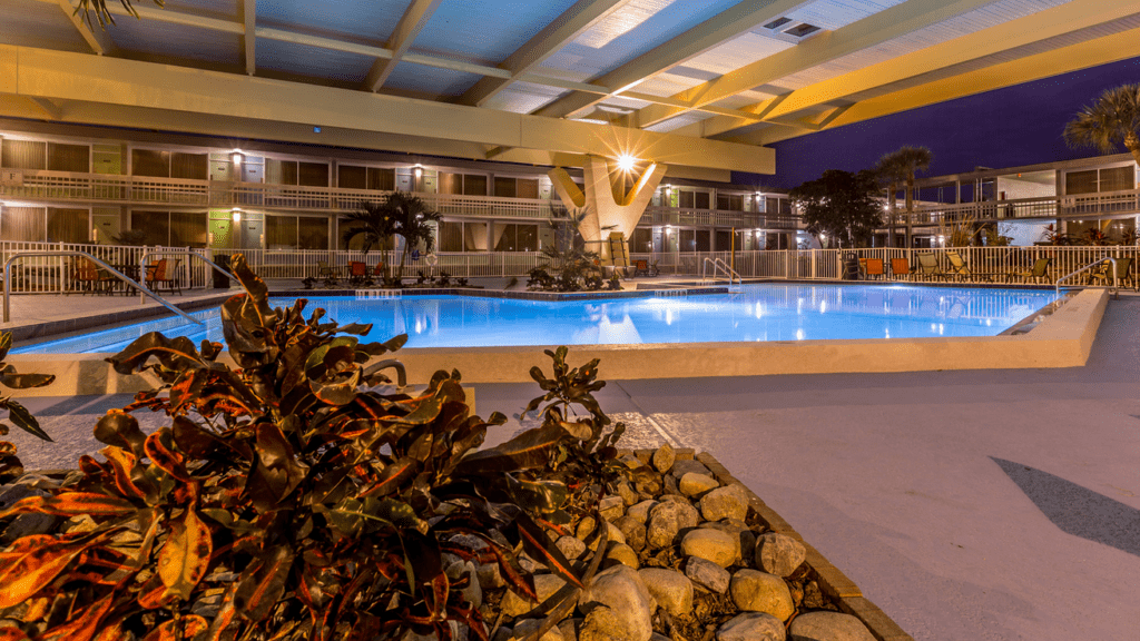 a pool with a large building and a large walkway