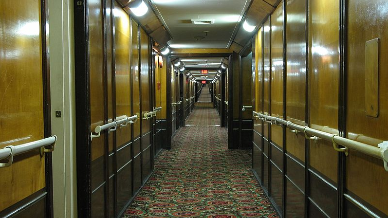 long hallway with wooden cabinets and carpet