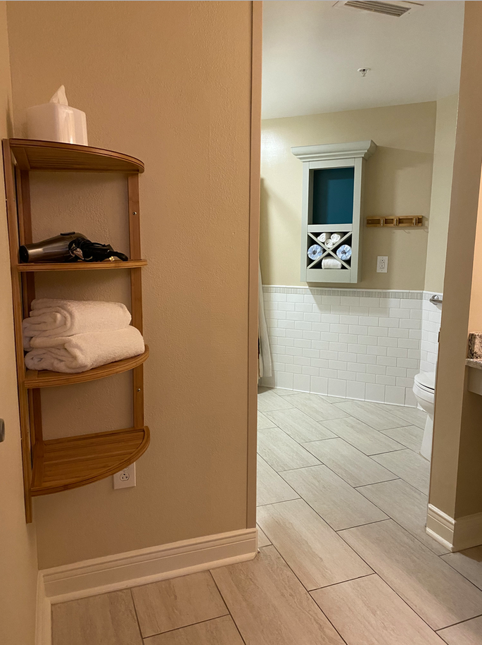 a bathroom with a shelf of towels and a toilet