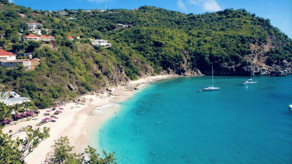 a beach with a sailboat in the water