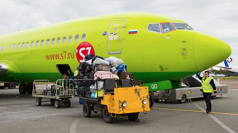 a cart with luggage on it next to a large green airplane