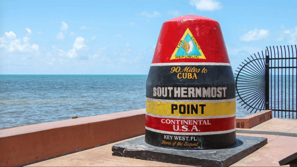 a red and black cone with a sign on it with Southernmost point buoy in the background