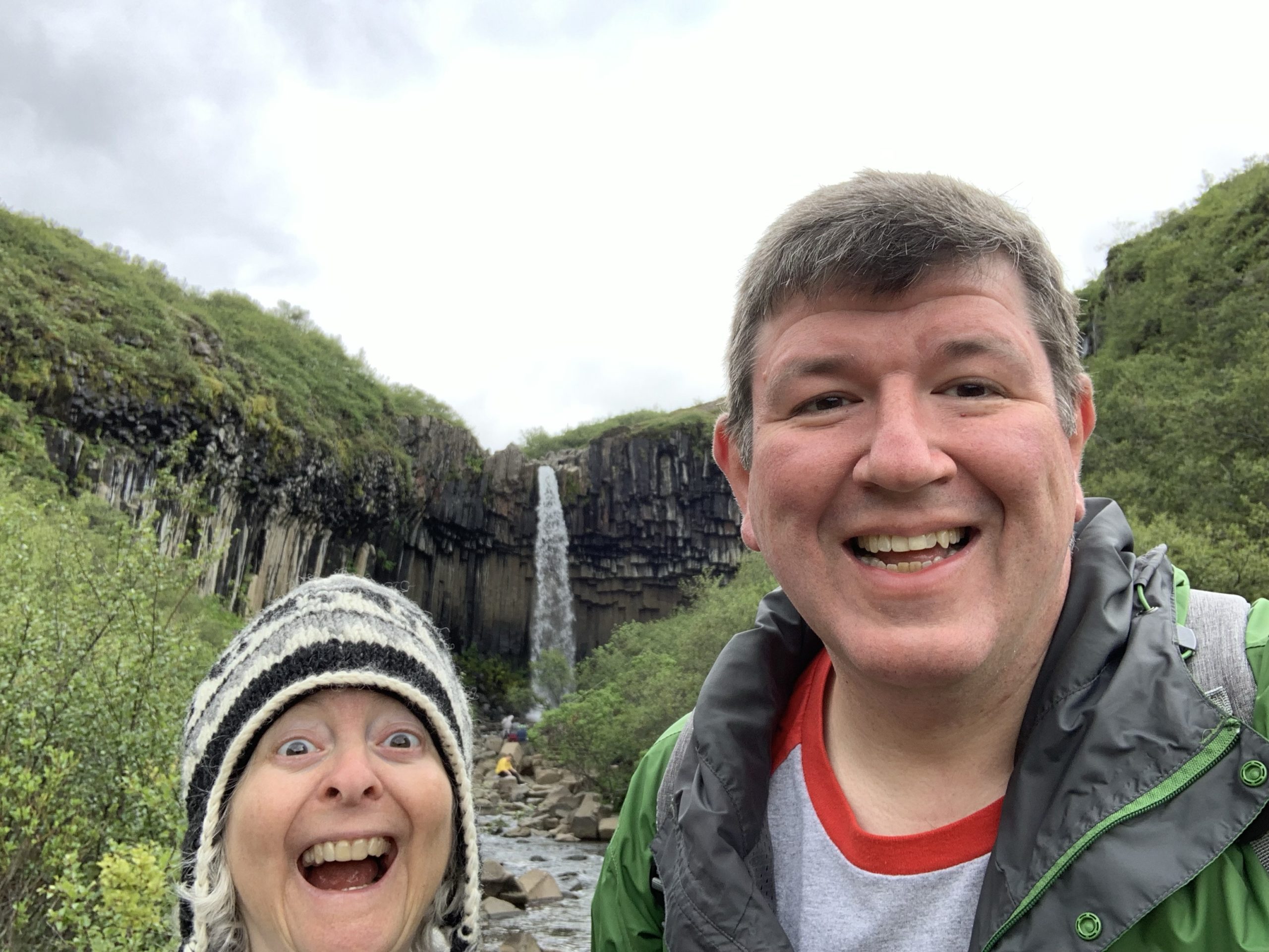 a man and woman taking a selfie in front of a waterfall