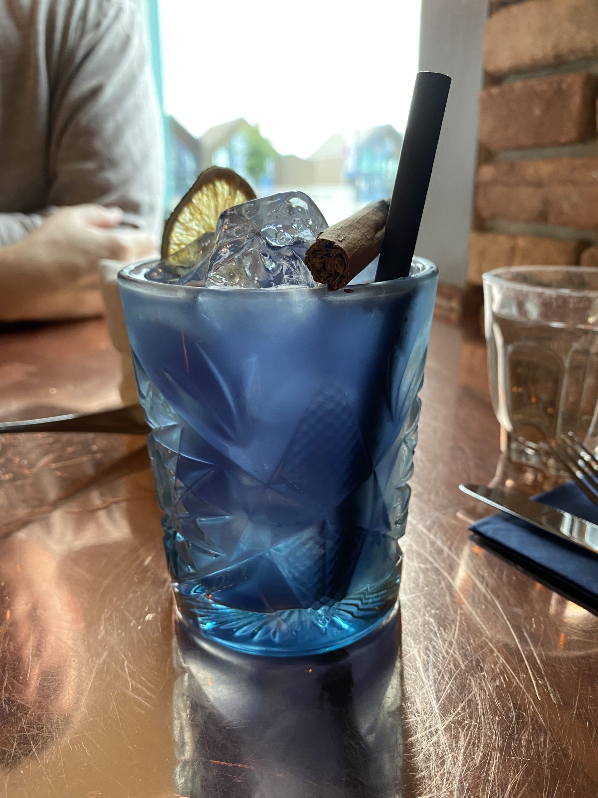 a blue drink with a straw and a cinnamon stick