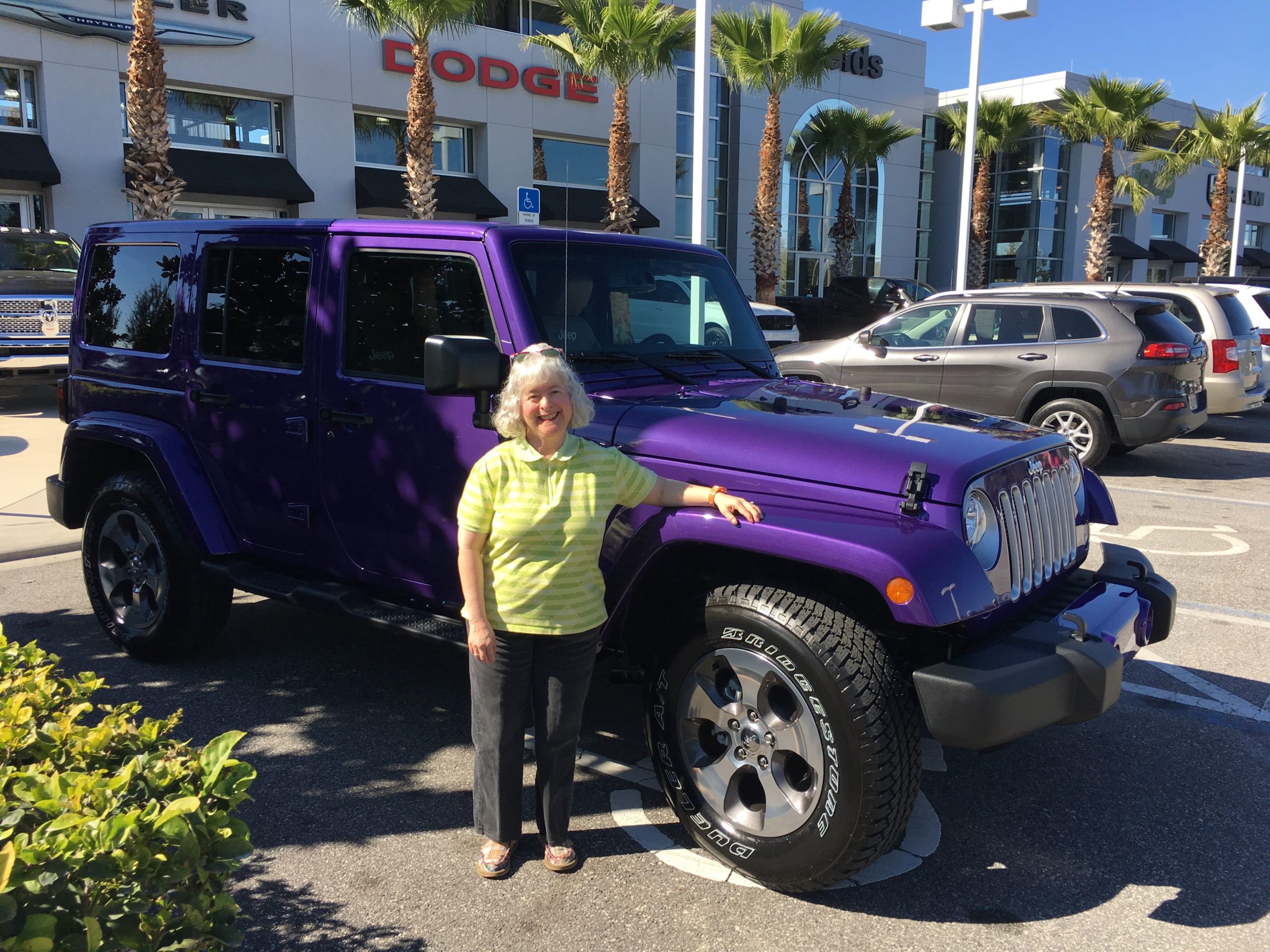 a woman standing next to a purple jeep