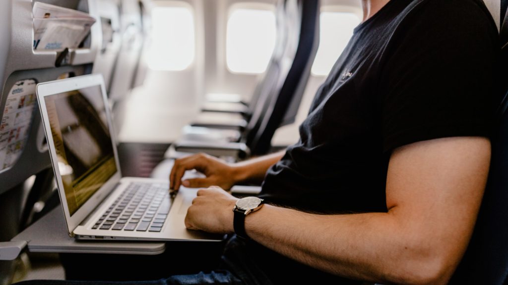 a man sitting on an airplane with a laptop