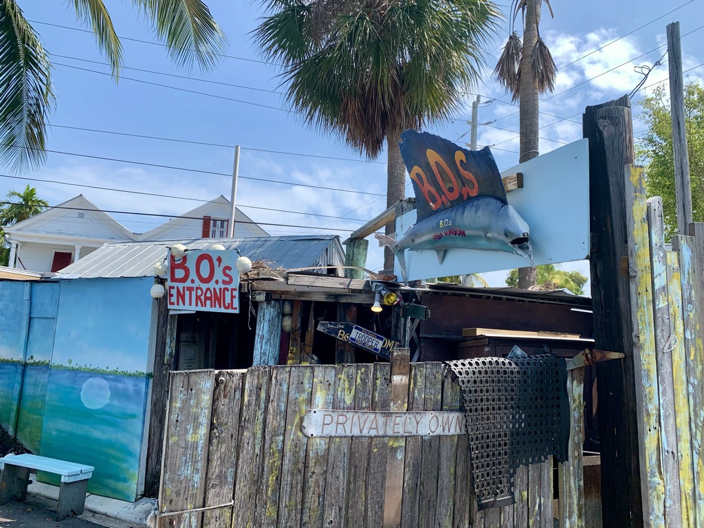 a wooden fence with a sign and palm trees