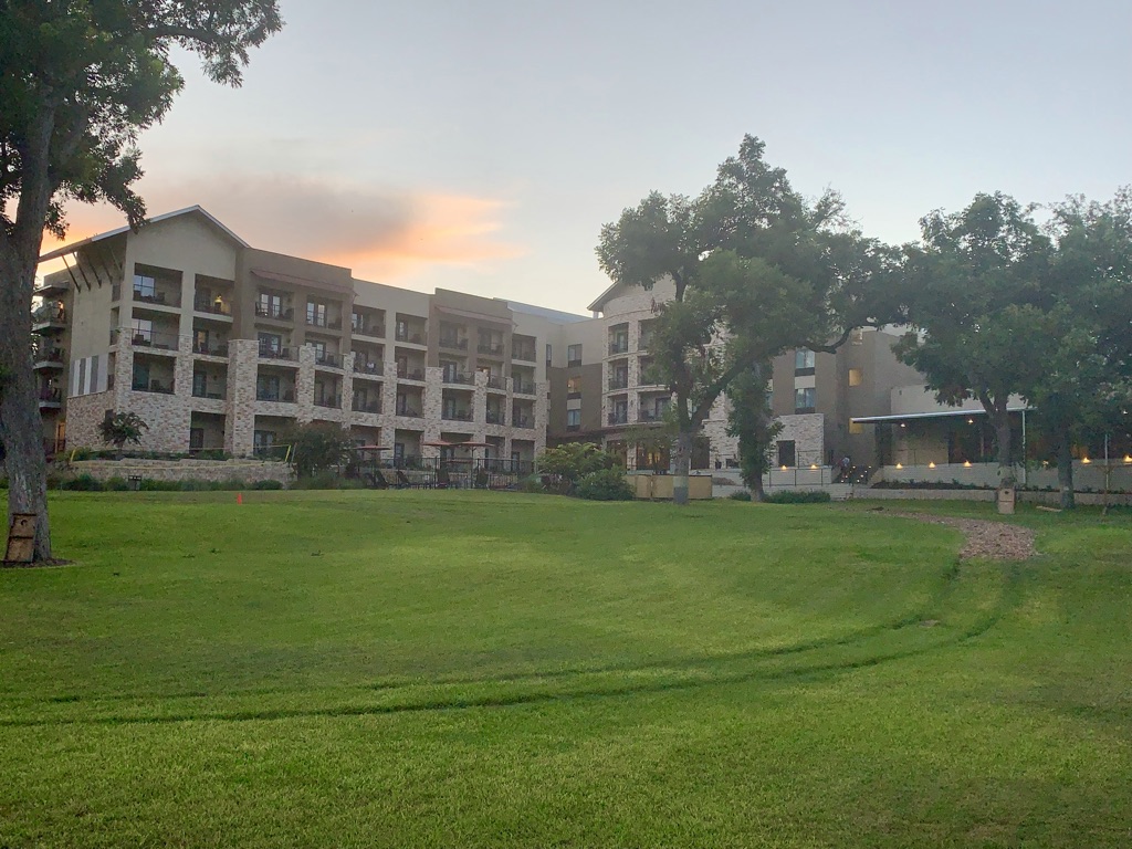 a large lawn with trees in front of a building