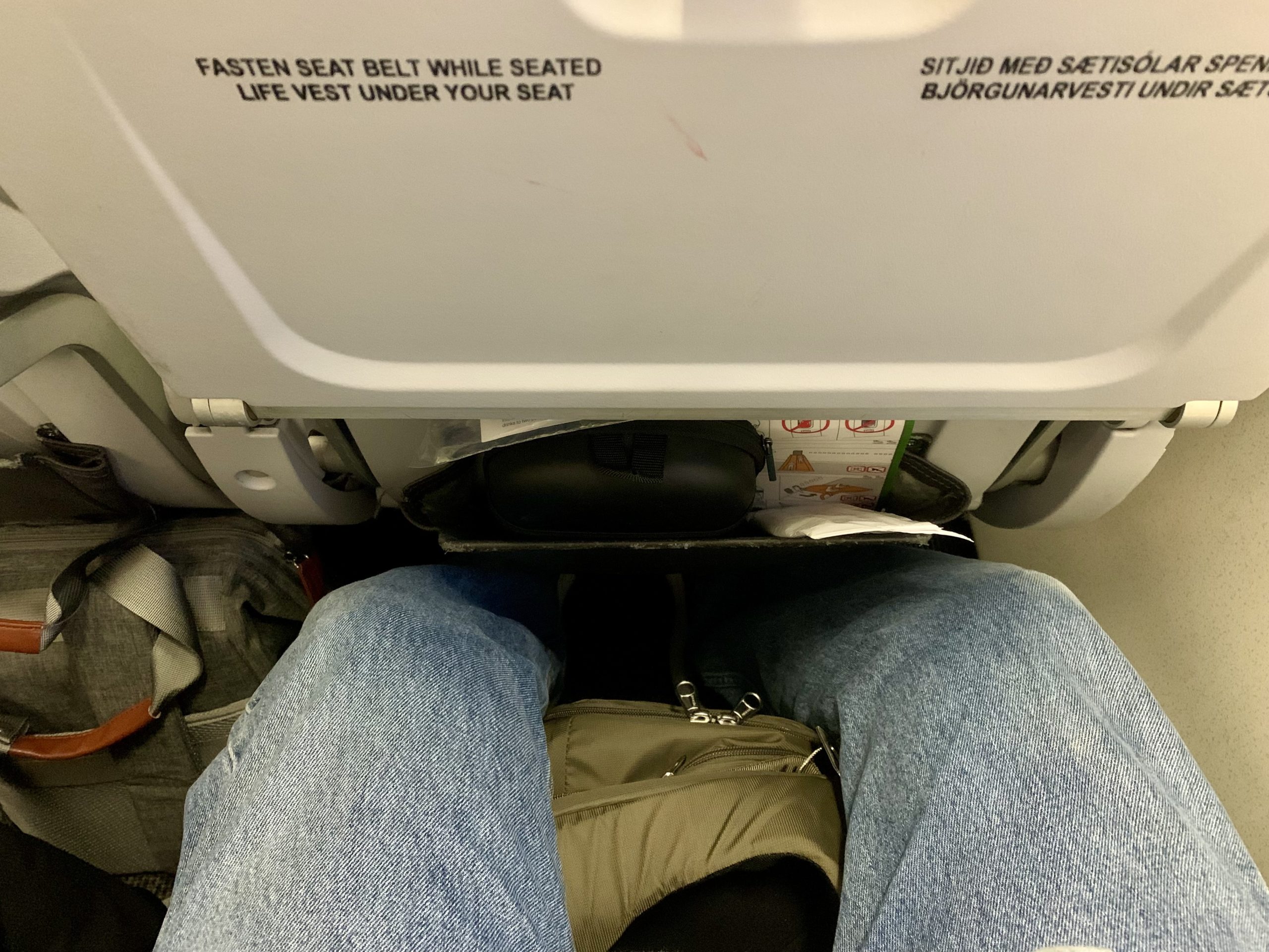 a person's legs under an airplane seat