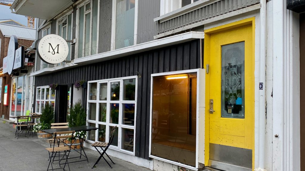 a yellow door with windows and chairs outside of a building