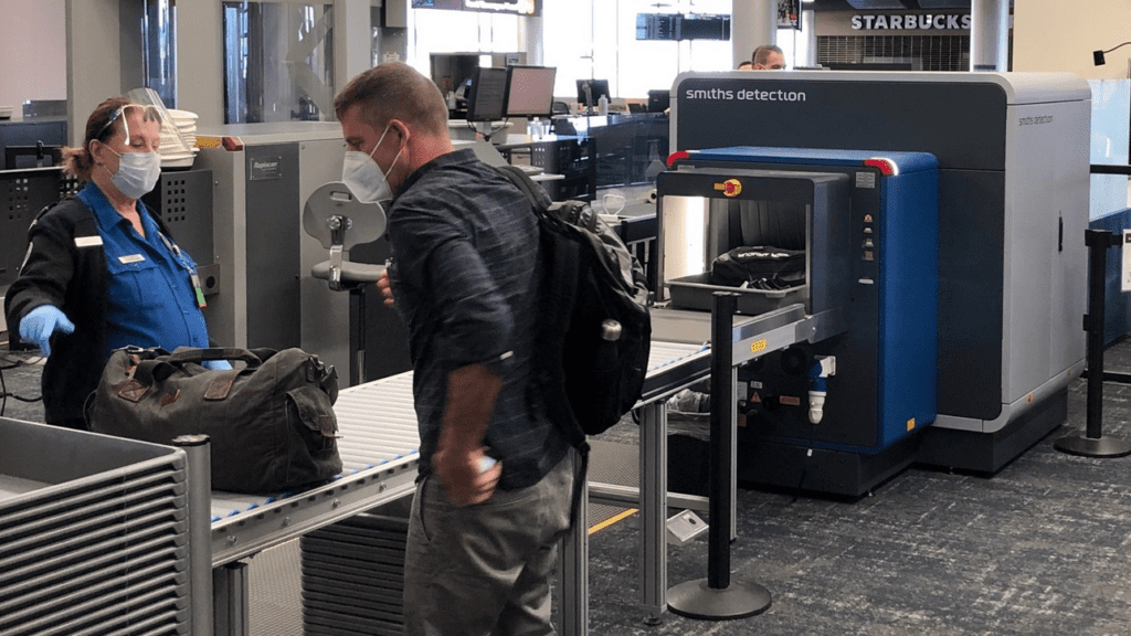 a man wearing a mask and standing next to a conveyor belt