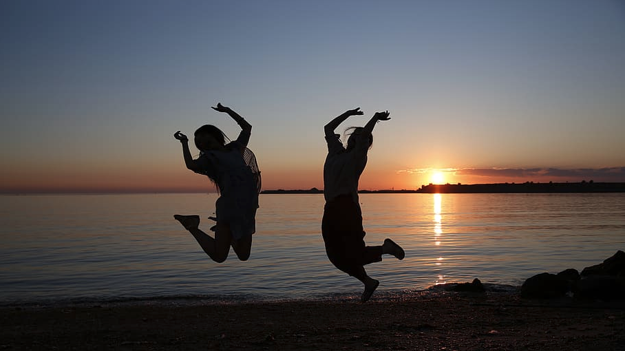 two women jumping in the air at the beach