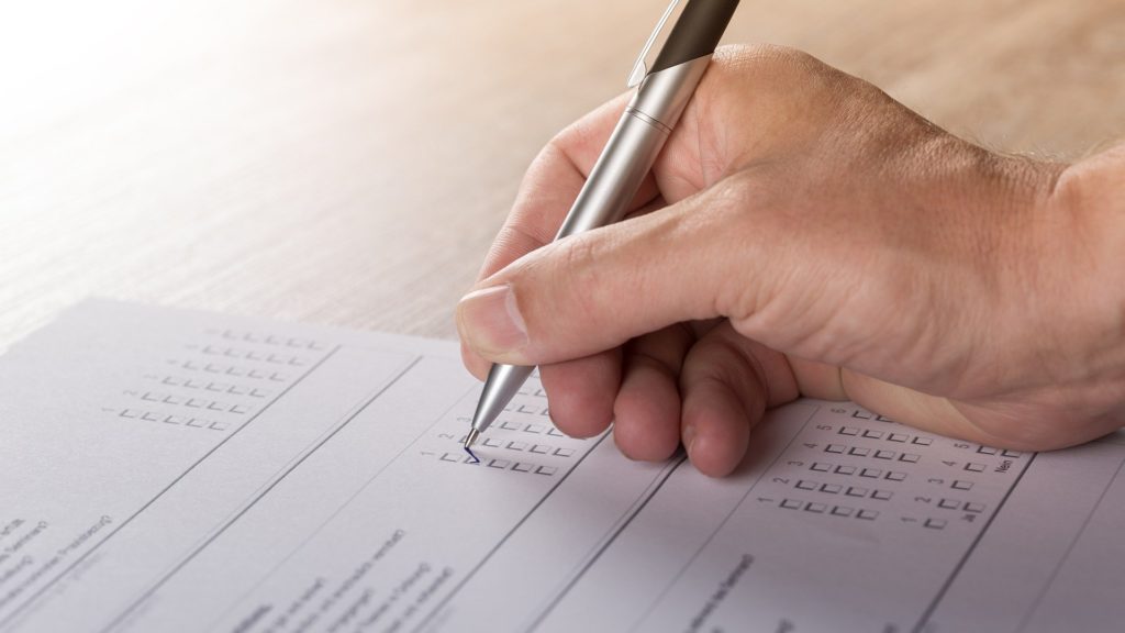 a hand holding a pen over a form