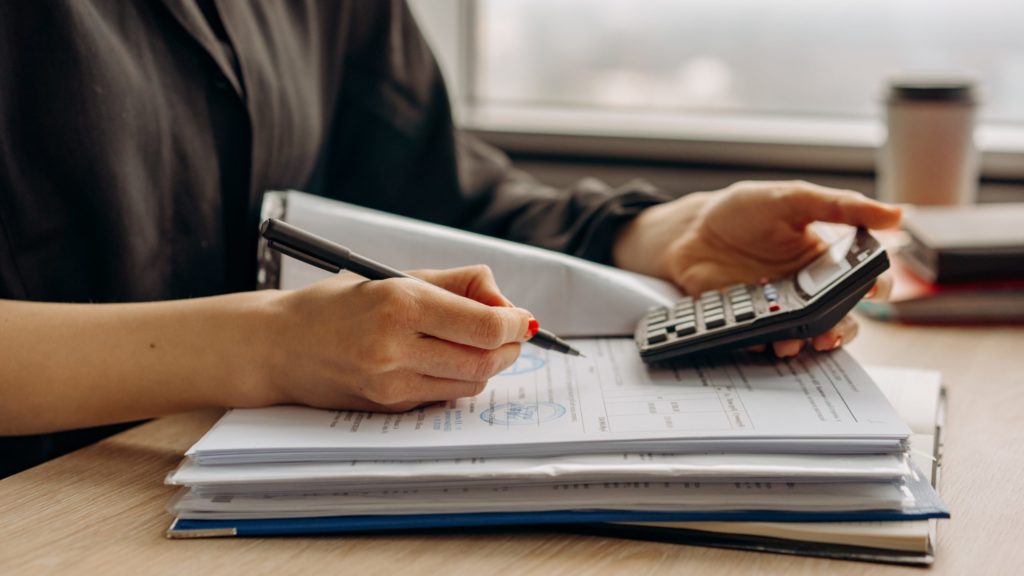 a person holding a pen and a calculator