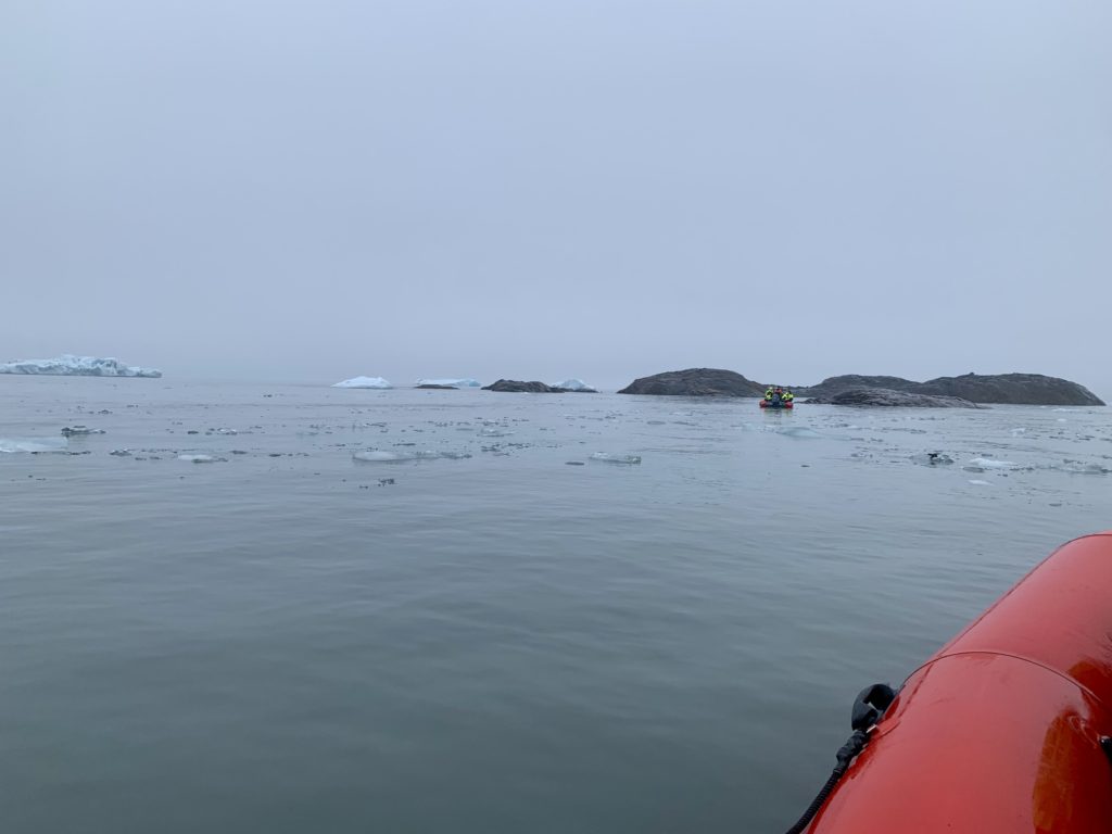 an inflatable raft in the water with icebergs in the background