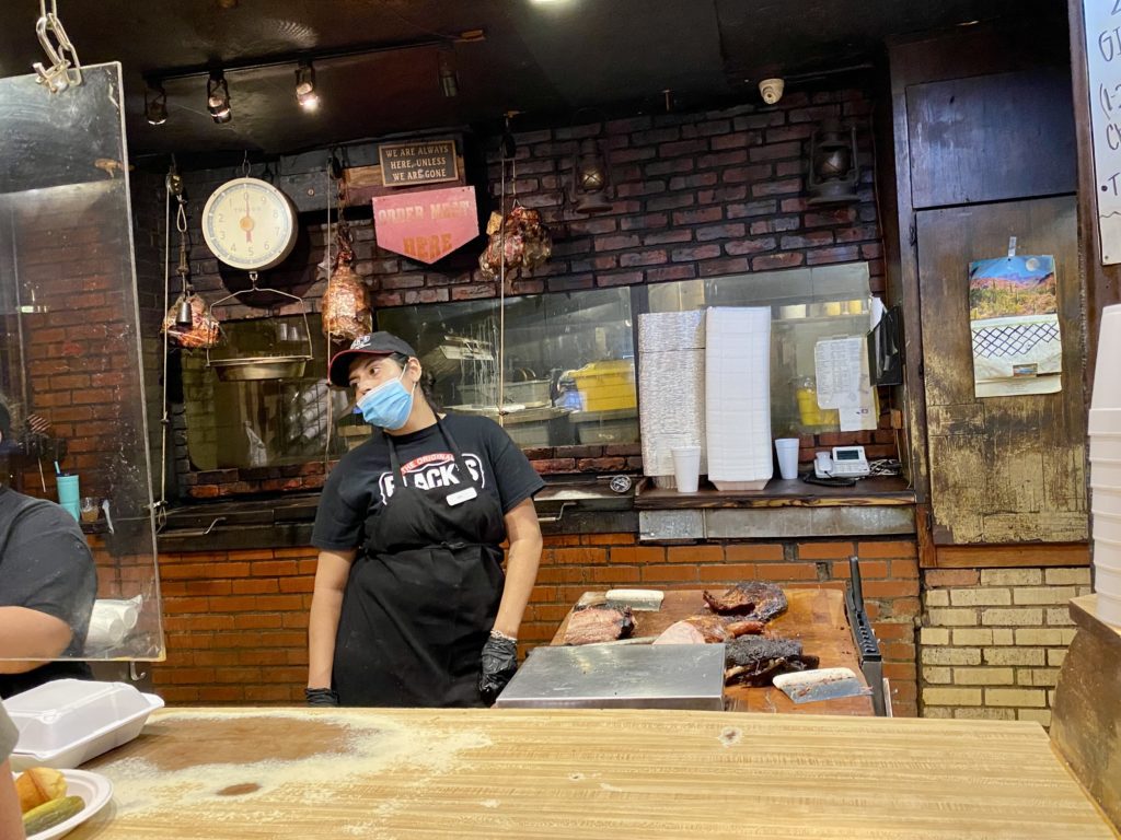 a man wearing a face mask standing in a butchery