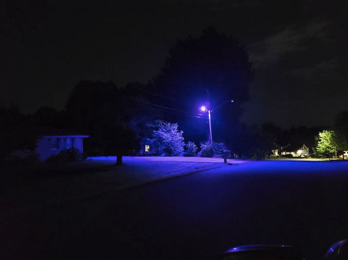 a street with a purple light at night