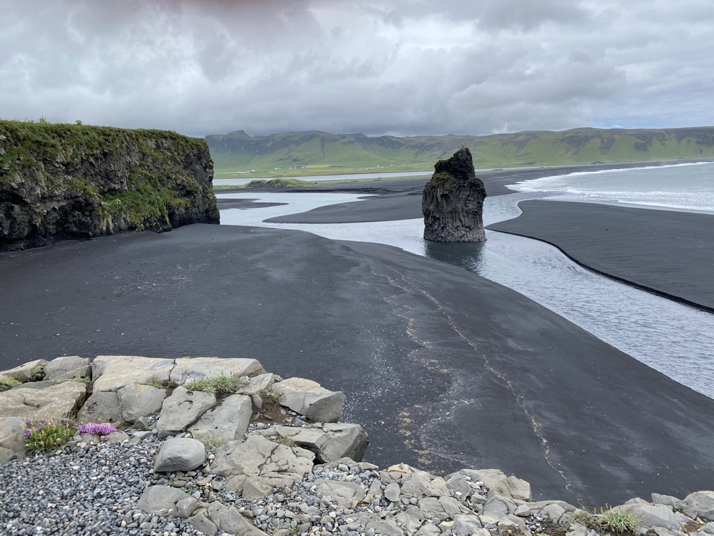 a black sand beach with a rock formation in the middle
