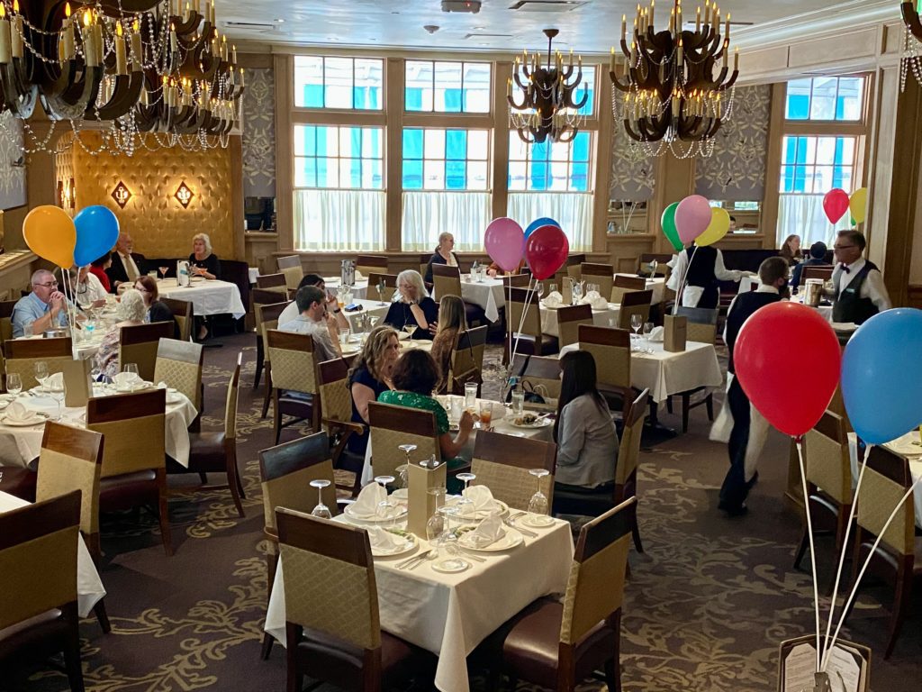 a group of people sitting at tables in a room with balloons