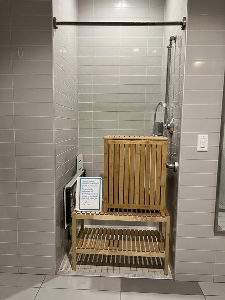 a shower with a wood shelf and a sign