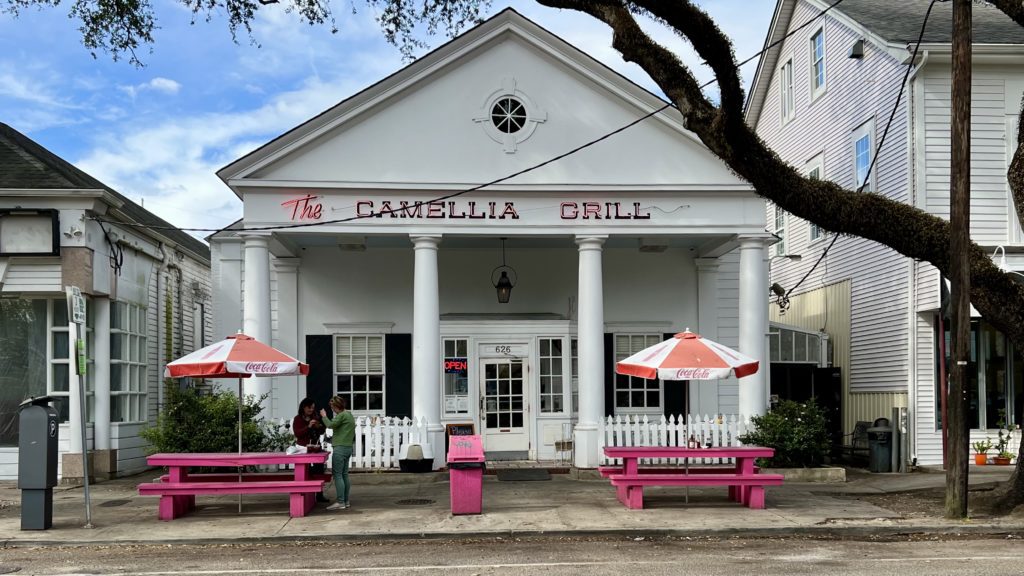 a white building with pink benches and umbrellas