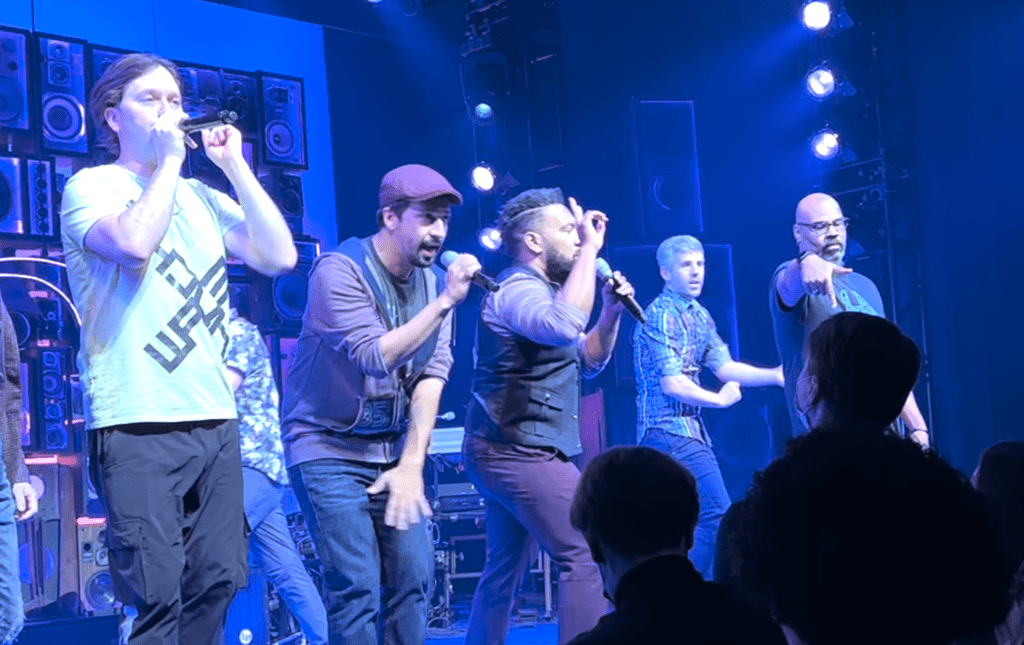 a group of men on a stage singing into microphones