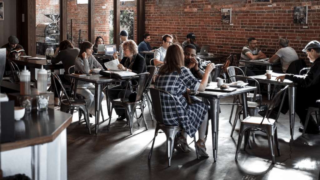 a group of people sitting at tables in a room with brick walls