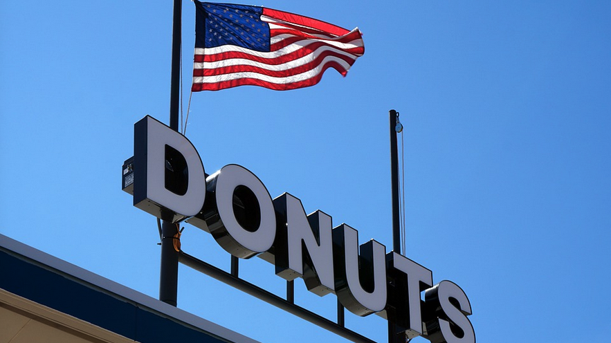 a flag flying on top of a donuts sign