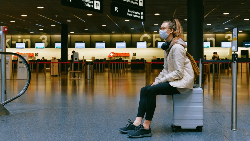 a woman sitting on a luggage in an airport