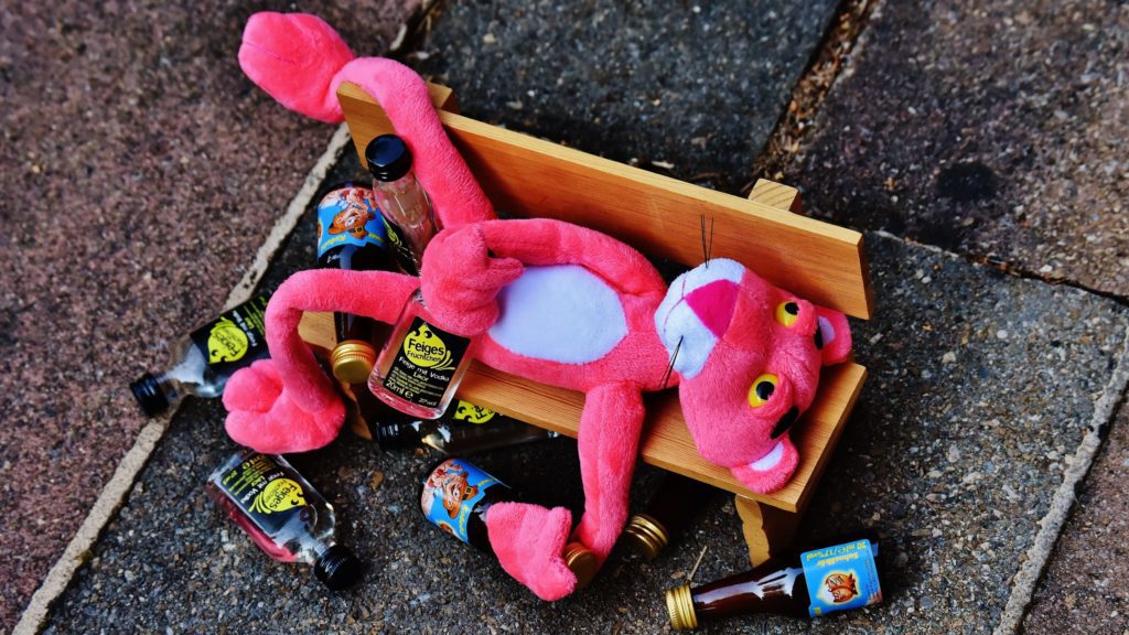 a stuffed animal on a bench with bottles on the ground