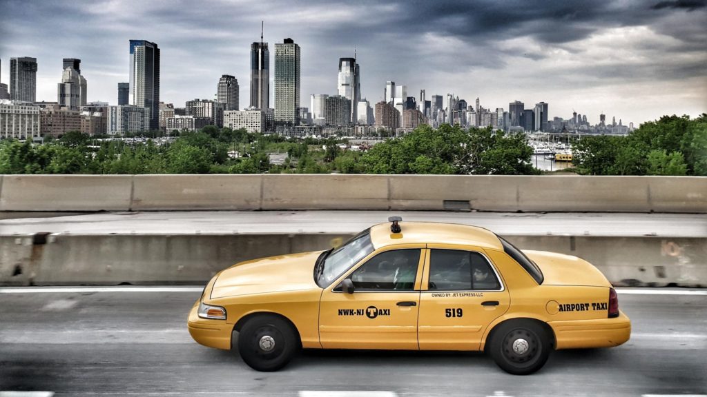 a yellow taxi on a bridge with a city in the background