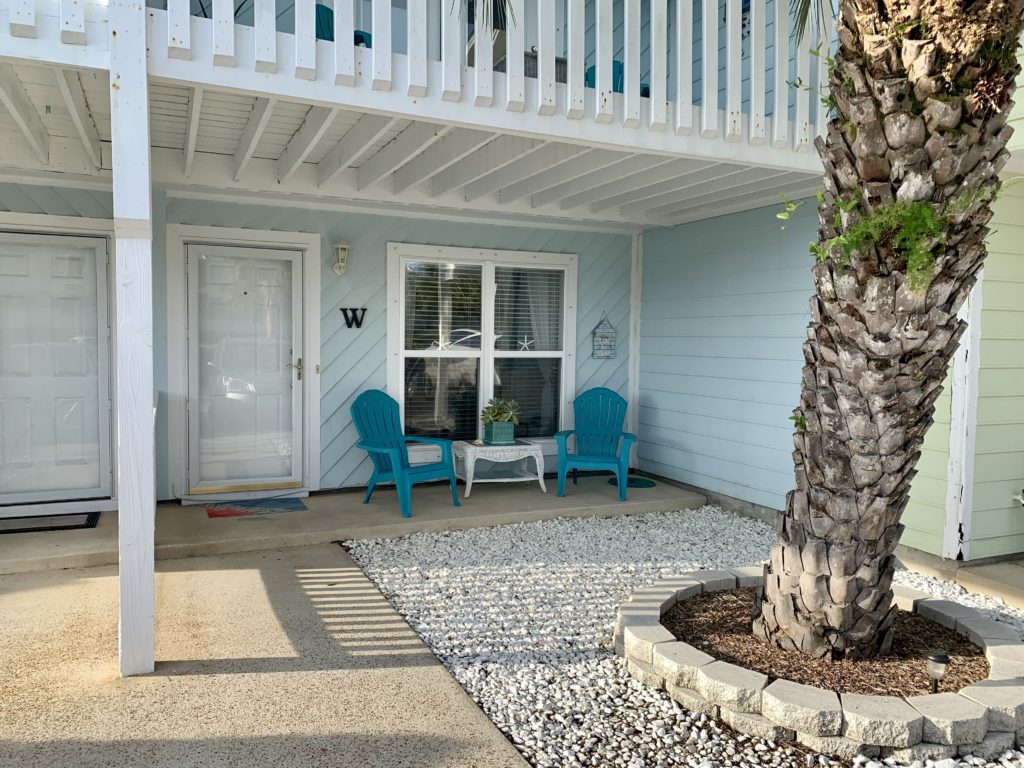 a blue house with white railing and blue chairs