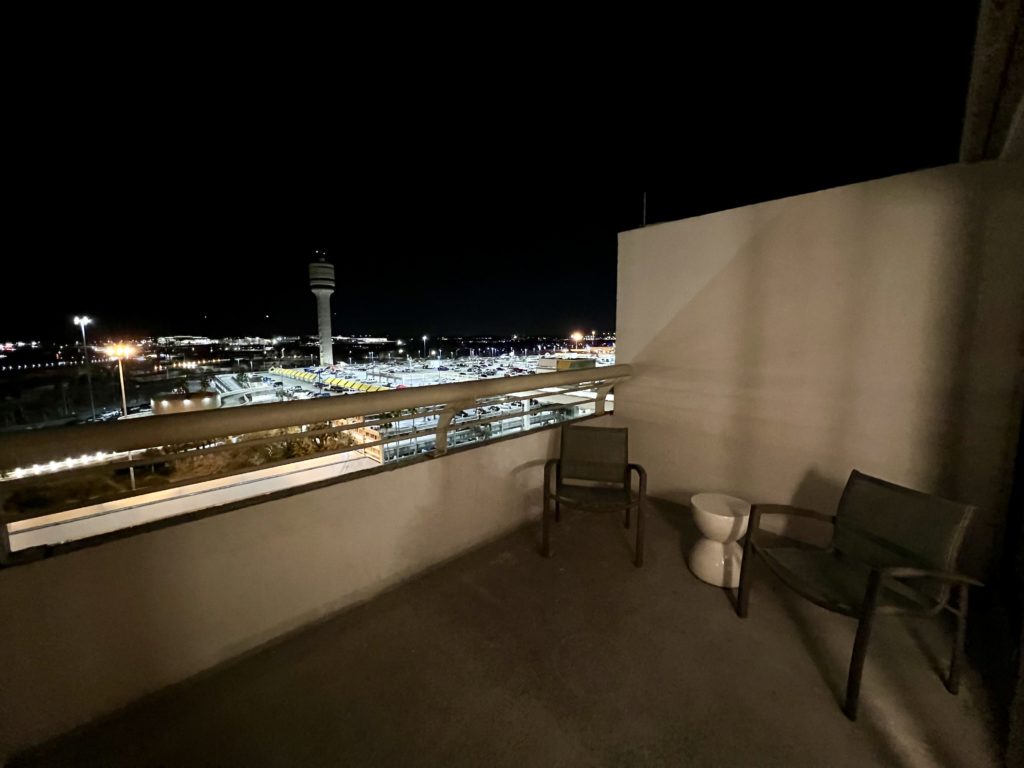 a balcony with chairs and a view of a city at night