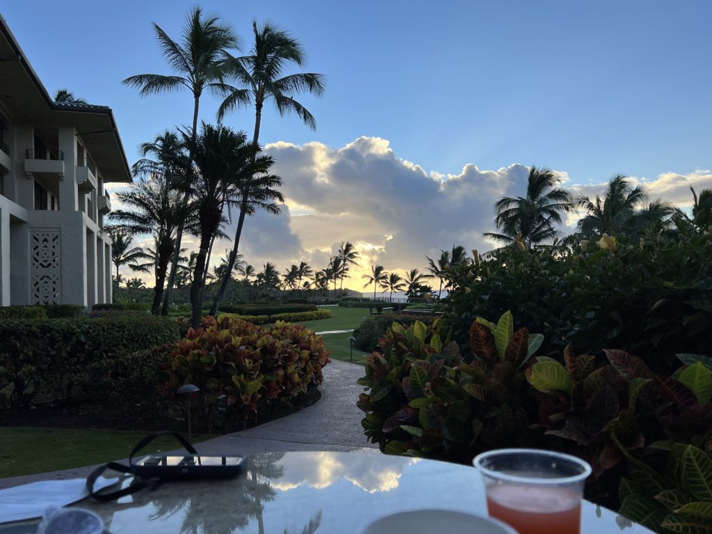 a table with a drink on it and palm trees in the background